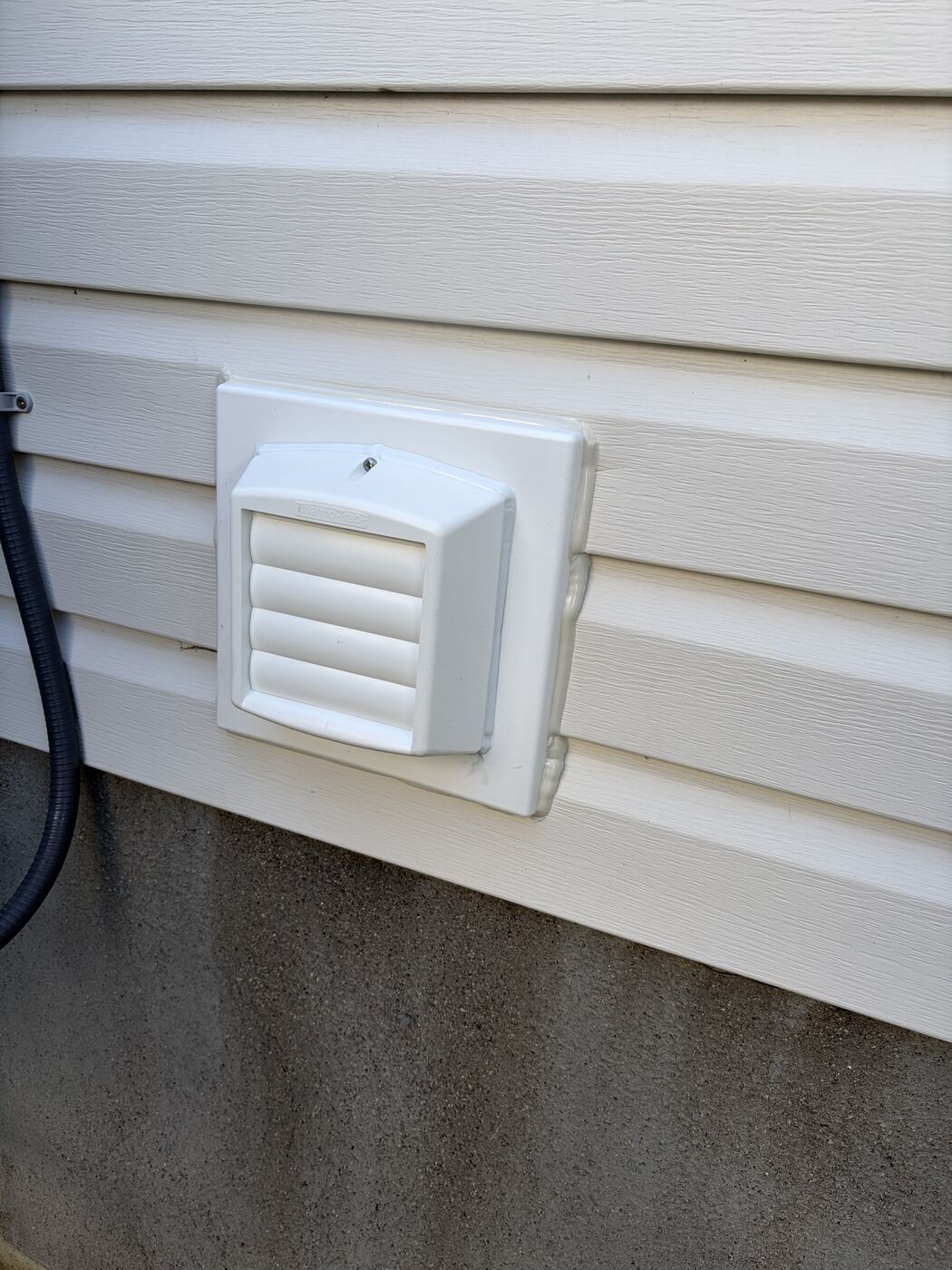 New commercial Thermo-Trap vent mounted and sealed near foundation