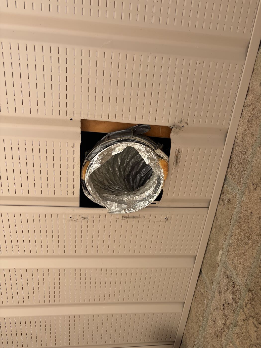 Open soffit hole with exposed foil duct held together with tape