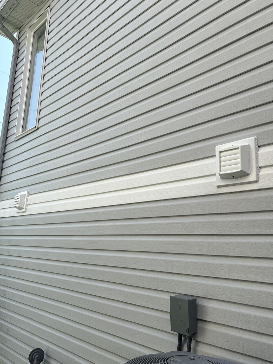 Two replacement vents on the same cream-sided wall of a Kanata home