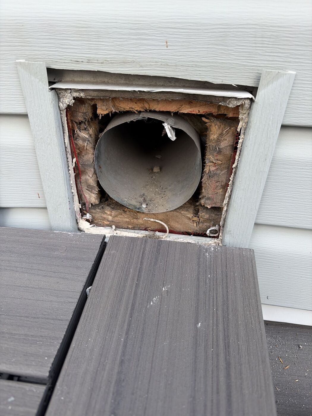 Old vent cover removed, showing a bare duct in an open wall cavity with fibreglass packed around it