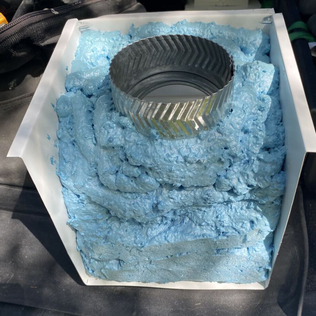 Inside of a soffit box showing the duct collar surrounded by closed-cell spray foam insulation