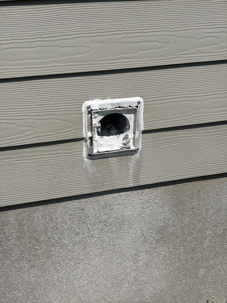 Exterior vent with the flap broken off and the open duct exposed on light siding