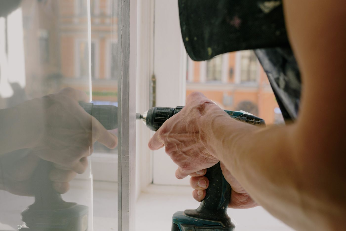 Worker driving a screw with a cordless drill while mounting an exterior fitting