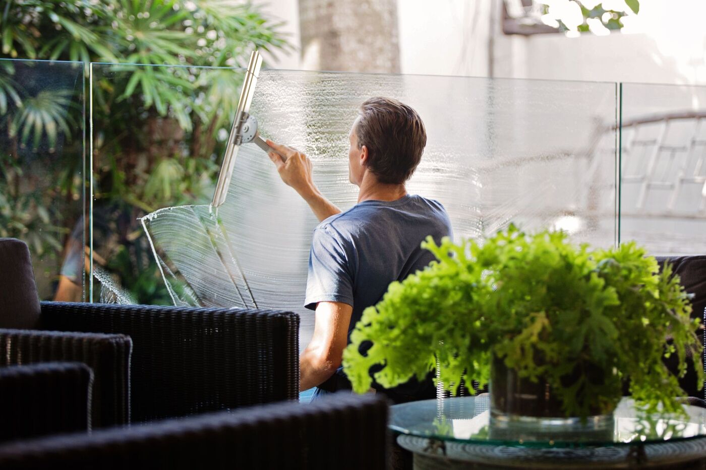 Window cleaner drawing a squeegee down freshly soaped glass