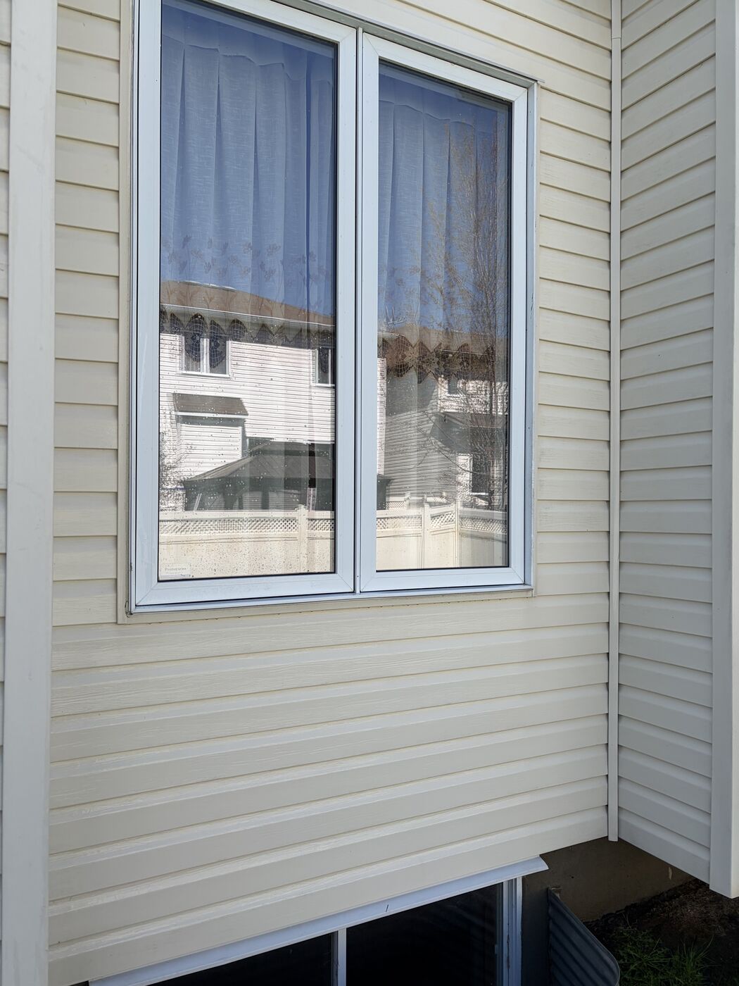 The same siding wall after low-pressure washing, back to an even cream colour with the finish undamaged
